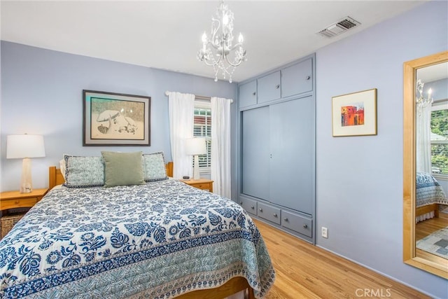 1107 Chestnut Ave, Redlands, CA 92373 - bedroom with a chandelier, light wood-style flooring, multiple windows, and a closet