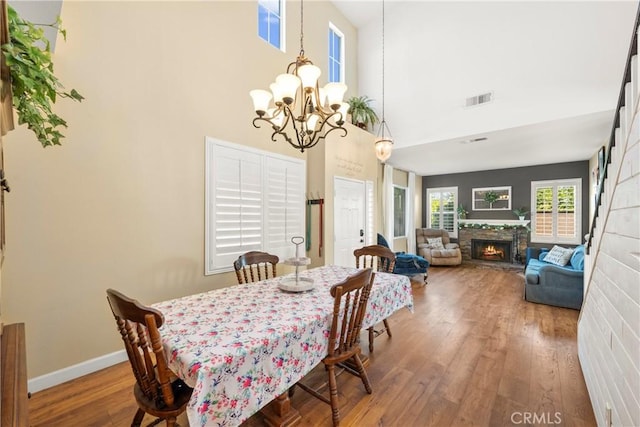 43611 Modena Dr, Temecula, CA 92592 - dining space featuring a chandelier, hardwood / wood-style floors, a fireplace, and a high ceiling