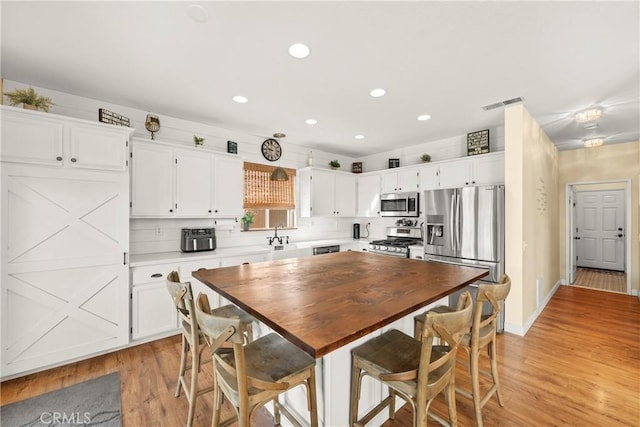 43611 Modena Dr, Temecula, CA 92592 - kitchen with appliances with stainless steel finishes, light wood-style floors, white cabinetry, recessed lighting, and butcher block countertops