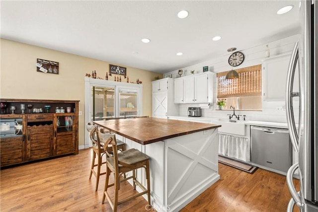 43611 Modena Dr, Temecula, CA 92592 - kitchen featuring butcher block countertops, stainless steel appliances, white cabinets, recessed lighting, and a breakfast bar