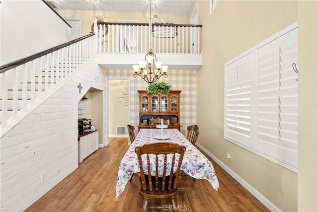 43611 Modena Dr, Temecula, CA 92592 - dining room featuring a chandelier, stairs, light wood-type flooring, and a towering ceiling