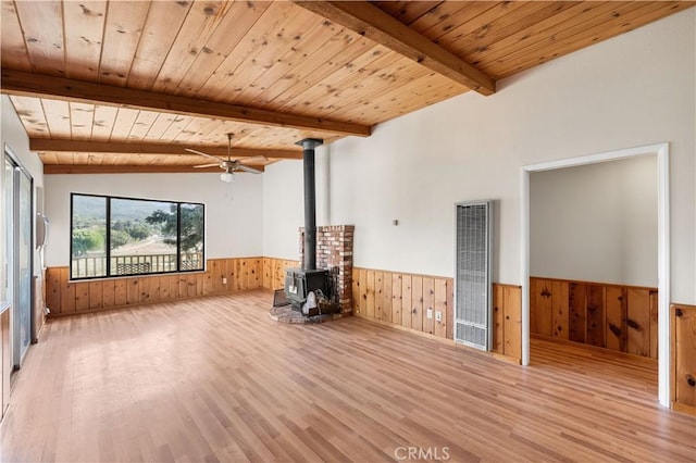 14526 Hardtree Dr, Lake Hughes, CA 93532 - unfurnished living room with a wainscoted wall, a heating unit, wooden walls, a wood stove, and a ceiling fan