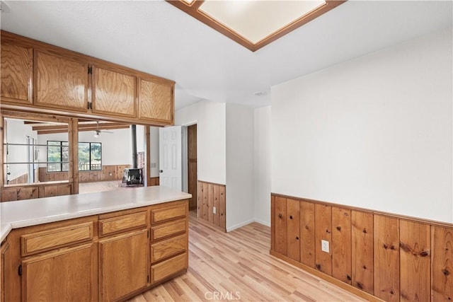 14526 Hardtree Dr, Lake Hughes, CA 93532 - kitchen with wainscoting, light wood-style floors, brown cabinets, light countertops, and wood walls