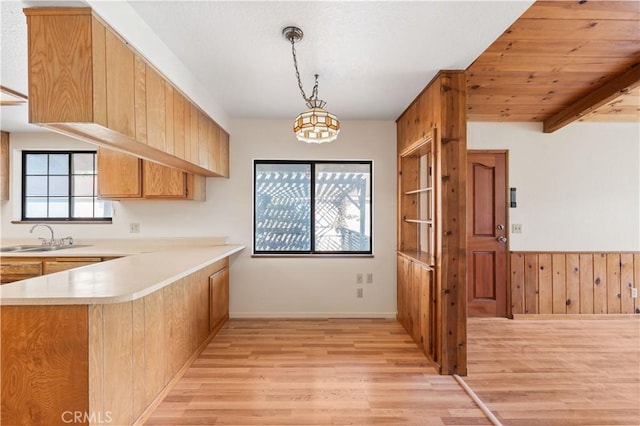 14526 Hardtree Dr, Lake Hughes, CA 93532 - kitchen featuring light wood finished floors, light countertops, a peninsula, wood walls, and hanging light fixtures