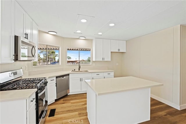 4369 Amador Rd, Phelan, CA 92371 - kitchen with appliances with stainless steel finishes, light wood finished floors, recessed lighting, white cabinets, and a center island
