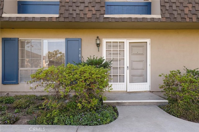4161 Elizabeth Ct, Cypress, CA 90630 - doorway to property featuring stucco siding, roof with shingles, and mansard roof
