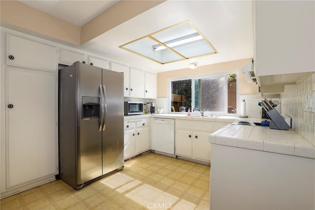4161 Elizabeth Ct, Cypress, CA 90630 - kitchen featuring stainless steel appliances, light floors, tile countertops, backsplash, and a skylight