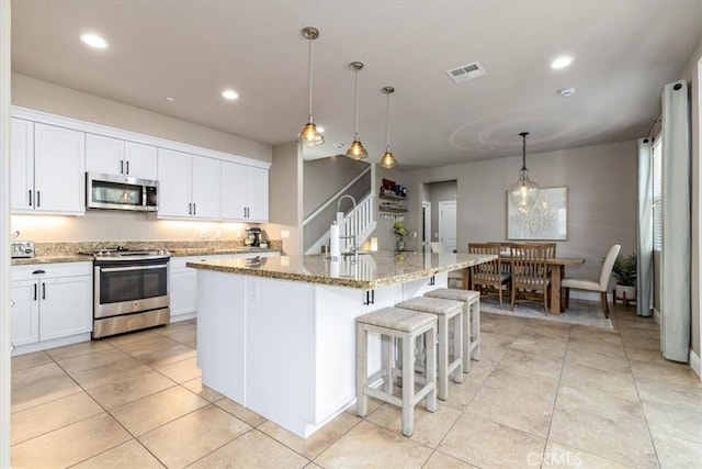 316 Junipero Way, San Luis Obispo, CA 93401 - kitchen with stainless steel appliances, light stone countertops, white cabinets, a kitchen island with sink, and light tile patterned floors