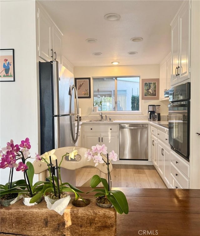 2148 Ronda Granada Unit A, Laguna Woods, CA 92637 - kitchen featuring appliances with stainless steel finishes, white cabinetry, and light wood-style floors