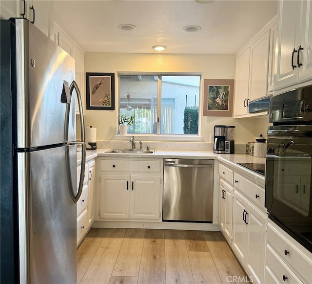 2148 Ronda Granada Unit A, Laguna Woods, CA 92637 - kitchen with black appliances, white cabinets, light wood finished floors, and light countertops