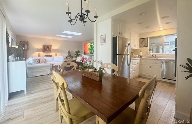 2148 Ronda Granada Unit A, Laguna Woods, CA 92637 - dining room featuring a chandelier, light wood-type flooring, healthy amount of natural light, and a skylight