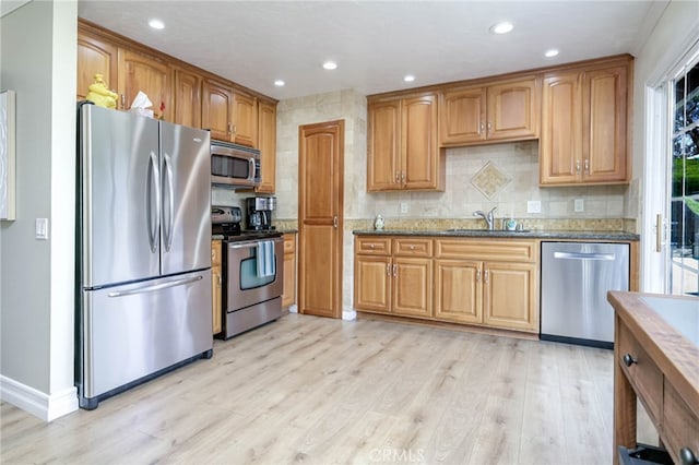 19851 Ridgewood Pl, Yorba Linda, CA 92886 - kitchen with appliances with stainless steel finishes, light wood-style floors, backsplash, dark stone countertops, and recessed lighting