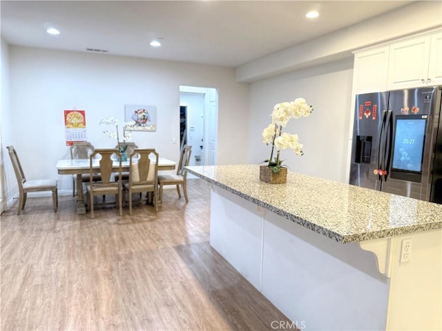 867 E Prommenade Unit B, Azusa, CA 91702 - kitchen with stainless steel fridge with ice dispenser, light stone countertops, a kitchen island, white cabinetry, and light wood-style floors