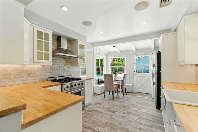 5517 Bevis Ave, Sherman Oaks, CA 91411 - kitchen with butcher block countertops, wall chimney exhaust hood, appliances with stainless steel finishes, light wood-style floors, and beamed ceiling