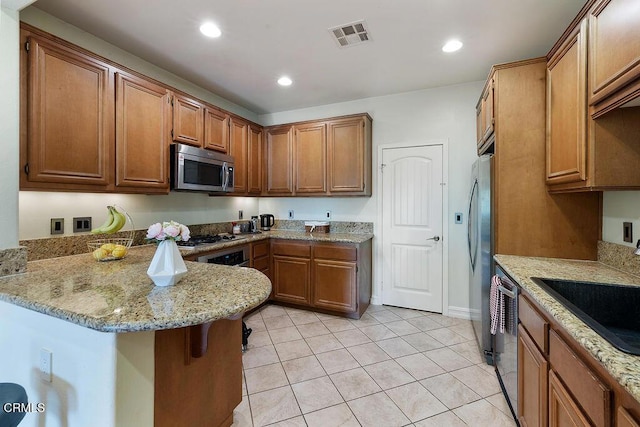 1430 Windshore Way, Oxnard, CA 93035 - kitchen with appliances with stainless steel finishes, a peninsula, light stone counters, light tile patterned floors, and brown cabinets