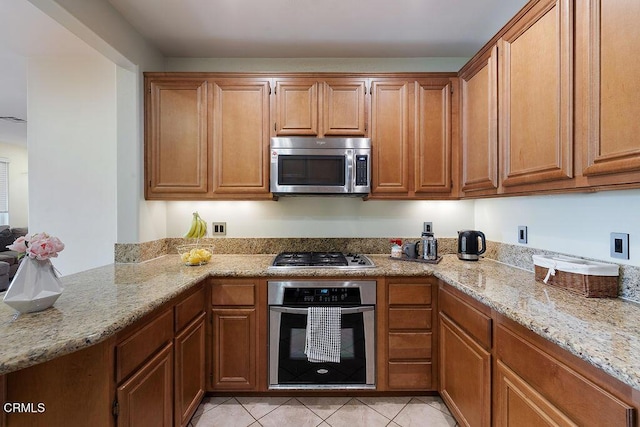 1430 Windshore Way, Oxnard, CA 93035 - kitchen featuring appliances with stainless steel finishes, light stone countertops, light tile patterned floors, and brown cabinetry