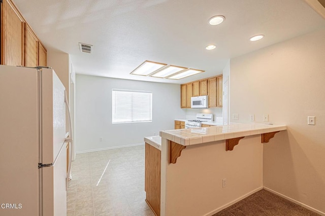 2400 Sunset Ridge Dr, Rosamond, CA 93560 - kitchen featuring white appliances, a breakfast bar area, a peninsula, recessed lighting, and tile countertops