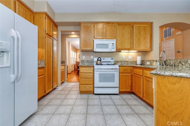13524 Via Santa Catalina, Sylmar, CA 91342 - kitchen featuring white appliances, arched walkways, light stone counters, light tile patterned floors, and brown cabinetry