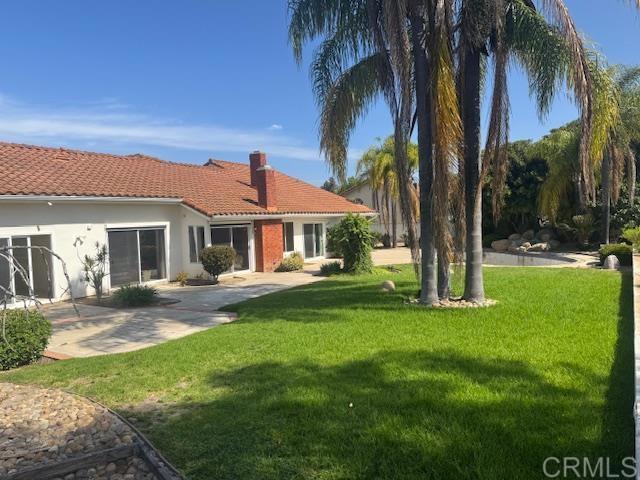 14109 Arbolitos Dr, Poway, CA 92064 - rear view of property featuring a yard, a tile roof, a chimney, stucco siding, and a patio area