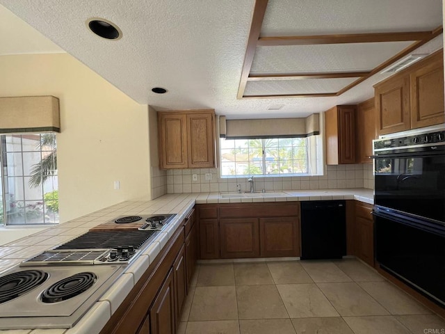 14109 Arbolitos Dr, Poway, CA 92064 - kitchen featuring black appliances, tasteful backsplash, a textured ceiling, brown cabinetry, and a peninsula