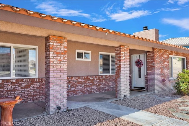 14616 Lighthouse Ln, Helendale, CA 92342 - doorway to property with brick siding, a chimney, covered porch, and a tile roof