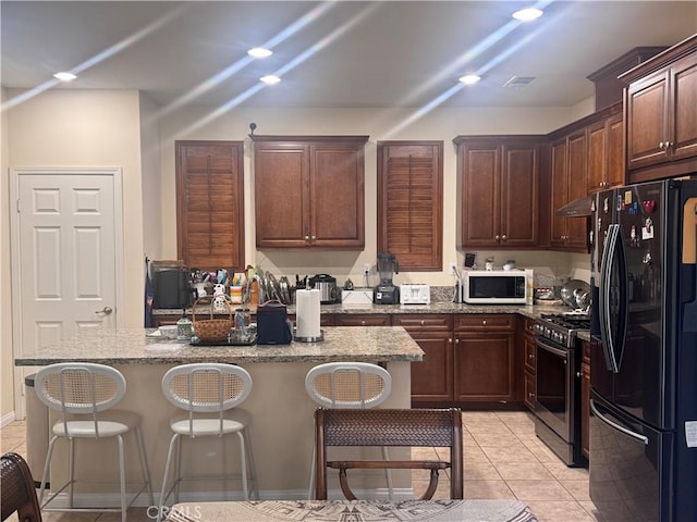 2944 E Via Terrano, Ontario, CA 91764 - kitchen featuring black refrigerator with ice dispenser, stainless steel gas range oven, white microwave, and a breakfast bar area