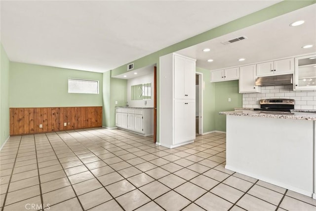 31 Pebblewood Pines Dr, Chico, CA 95926 - kitchen with stainless steel range with electric cooktop, under cabinet range hood, white cabinets, wooden walls, and wainscoting