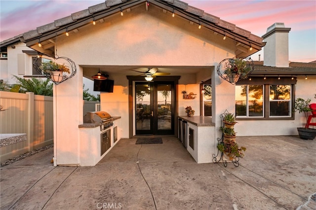 32872 Northshire Cir, Temecula, CA 92592 - exterior entry at dusk with area for grilling, a patio, french doors, ceiling fan, and stucco siding