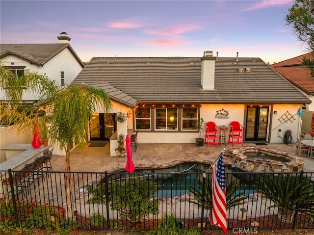 32872 Northshire Cir, Temecula, CA 92592 - back of house at dusk with an outdoor hot tub, a fenced backyard, stucco siding, a tile roof, and a patio