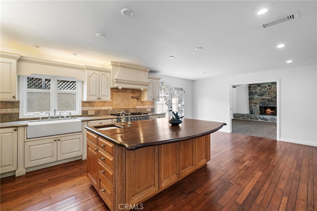 2030 Goldeneye Pl, Costa Mesa, CA 92626 - kitchen featuring dark countertops, custom exhaust hood, dark wood finished floors, an island with sink, and tasteful backsplash
