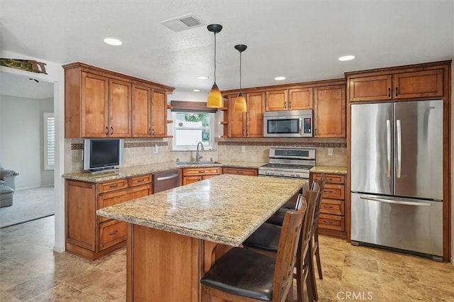 15144 Poppy Meadow St, Canyon Country, CA 91387 - kitchen with appliances with stainless steel finishes, brown cabinetry, a center island, backsplash, and recessed lighting