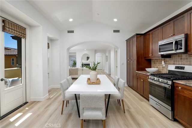 74 Townsend, Irvine, CA 92620 - kitchen with appliances with stainless steel finishes, arched walkways, tasteful backsplash, light wood-style flooring, and lofted ceiling