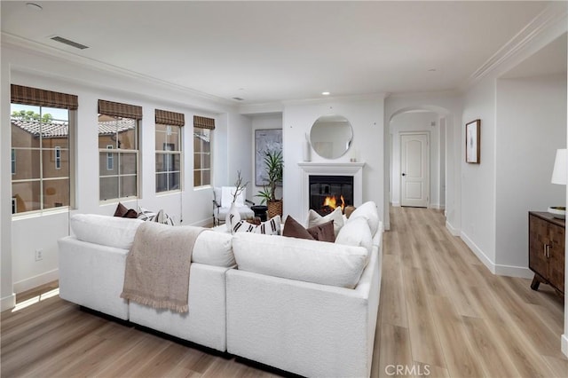 74 Townsend, Irvine, CA 92620 - living room with light wood-style flooring, arched walkways, a glass covered fireplace, crown molding, and recessed lighting