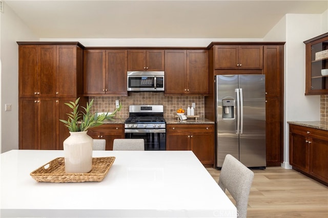74 Townsend, Irvine, CA 92620 - kitchen featuring stainless steel appliances, tasteful backsplash, light wood finished floors, and light stone counters