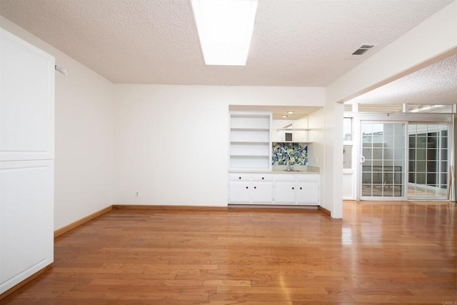 3621 Vista Campana S Unit 11, Oceanside, CA 92057 - unfurnished living room featuring a textured ceiling and light wood-style floors