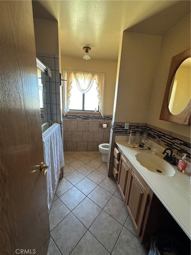 18211 Hercules St, Hesperia, CA 92345 - bathroom featuring vanity, tile walls, tile patterned flooring, a stall shower, and a wainscoted wall
