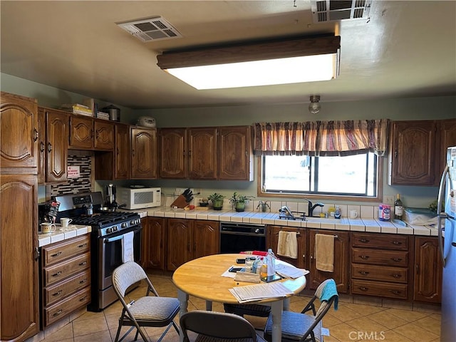 18211 Hercules St, Hesperia, CA 92345 - kitchen featuring appliances with stainless steel finishes, tile counters, and light tile patterned flooring