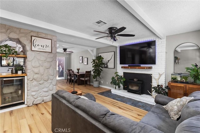 4913 Sparrow Hawk Ln, Paso Robles, CA 93446 - living room with a textured ceiling, a ceiling fan, beverage cooler, wood finished floors, and a wood stove