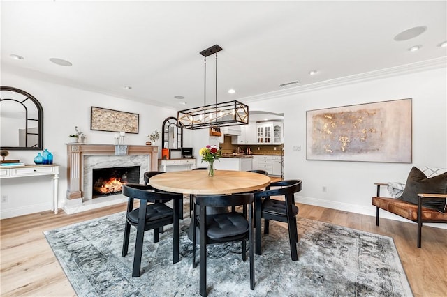 2726 Cardinal Dr, Costa Mesa, CA 92626 - dining area with a high end fireplace, light wood finished floors, crown molding, and recessed lighting