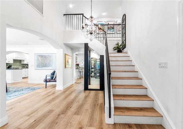 2726 Cardinal Dr, Costa Mesa, CA 92626 - stairway with arched walkways, a chandelier, wood finished floors, and a towering ceiling