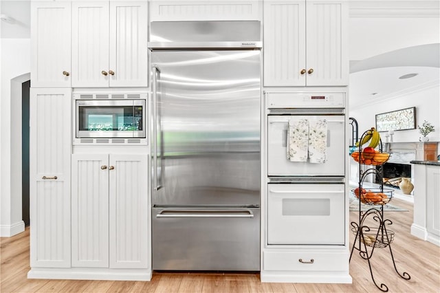 2726 Cardinal Dr, Costa Mesa, CA 92626 - kitchen featuring built in appliances, crown molding, light wood-type flooring, and arched walkways