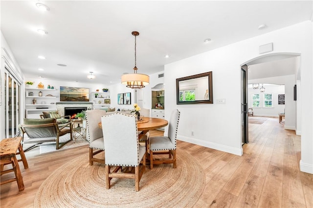 2726 Cardinal Dr, Costa Mesa, CA 92626 - dining room with a warm lit fireplace, light wood-style flooring, a chandelier, arched walkways, and recessed lighting