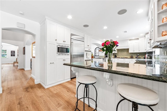 2726 Cardinal Dr, Costa Mesa, CA 92626 - kitchen featuring built in appliances, arched walkways, a peninsula, white cabinets, and recessed lighting