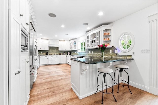 2726 Cardinal Dr, Costa Mesa, CA 92626 - kitchen with a peninsula, backsplash, glass insert cabinets, white cabinets, and recessed lighting