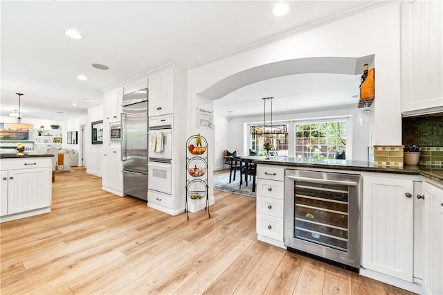 2726 Cardinal Dr, Costa Mesa, CA 92626 - kitchen with wine cooler, dark countertops, stainless steel built in refrigerator, white cabinets, and recessed lighting