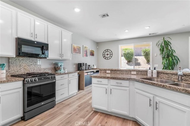 3871 Bur Oak Rd, San Bernardino, CA 92407 - kitchen with stainless steel gas range oven, black microwave, white cabinetry, light wood finished floors, and tasteful backsplash