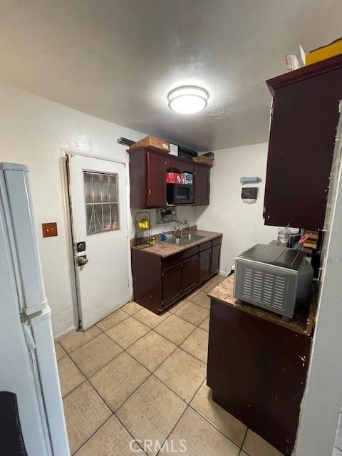 8014 Morton Ave, Los Angeles, CA 90001 - kitchen with freestanding refrigerator, light tile patterned floors, dark brown cabinets, and light countertops