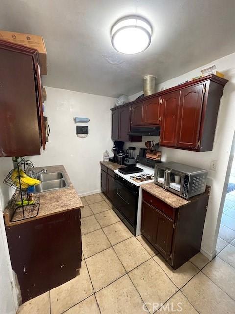 8014 Morton Ave, Los Angeles, CA 90001 - kitchen with gas range, under cabinet range hood, light tile patterned flooring, and light countertops