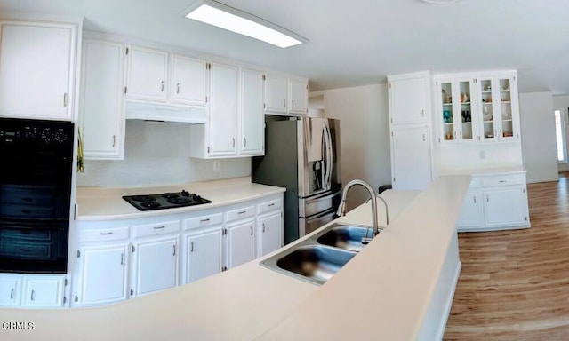 21613 Mountain Dr, Tehachapi, CA 93561 - kitchen featuring stainless steel refrigerator with ice dispenser, black electric stovetop, under cabinet range hood, white cabinetry, and light wood finished floors