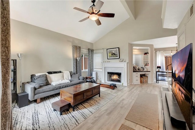 30042 Oceanus, Laguna Niguel, CA 92677 - living room featuring high vaulted ceiling, ceiling fan, a warm lit fireplace, and wood finished floors